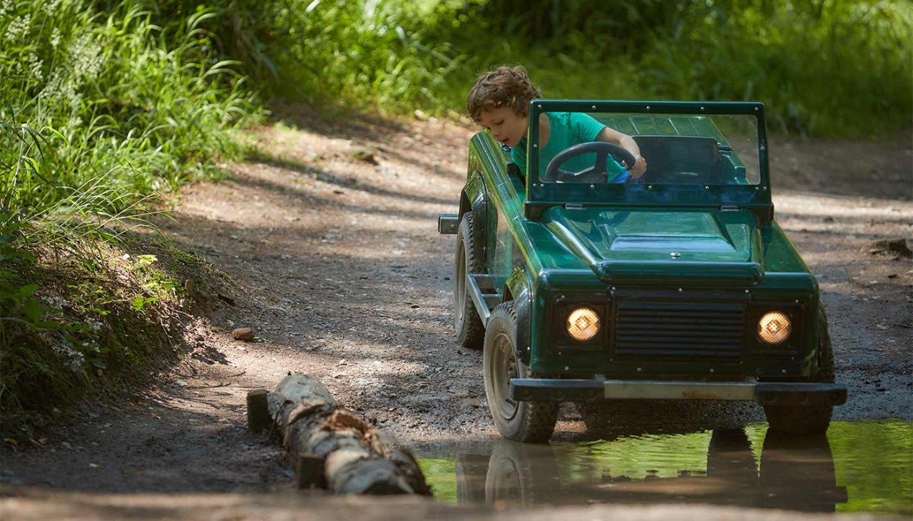 A young boy drivning a mini truck throught the forest