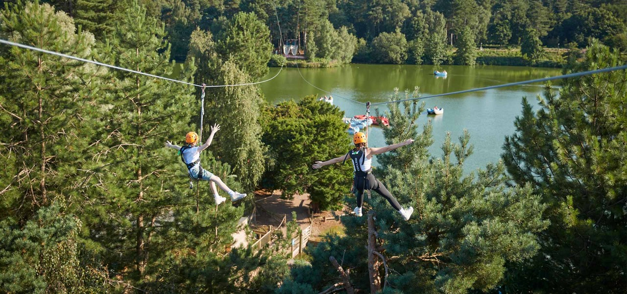 Brother and sister on the zipline going over the lake.